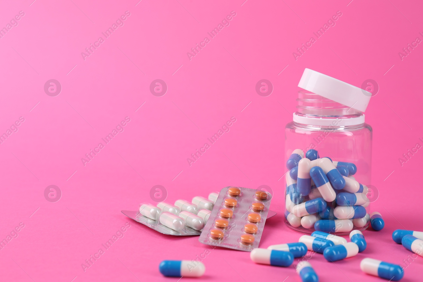 Photo of Pharmacist. Many different pills on pink background