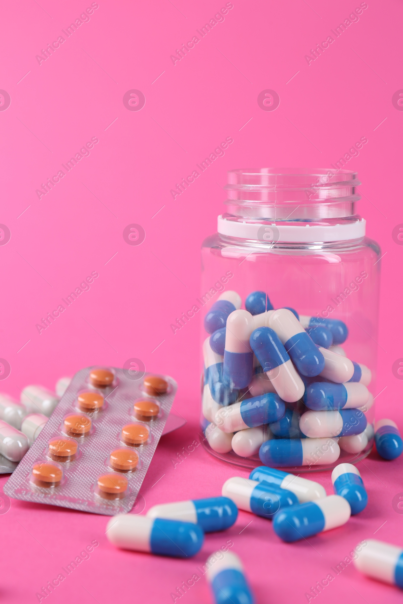 Photo of Pharmacist. Many different pills on pink background