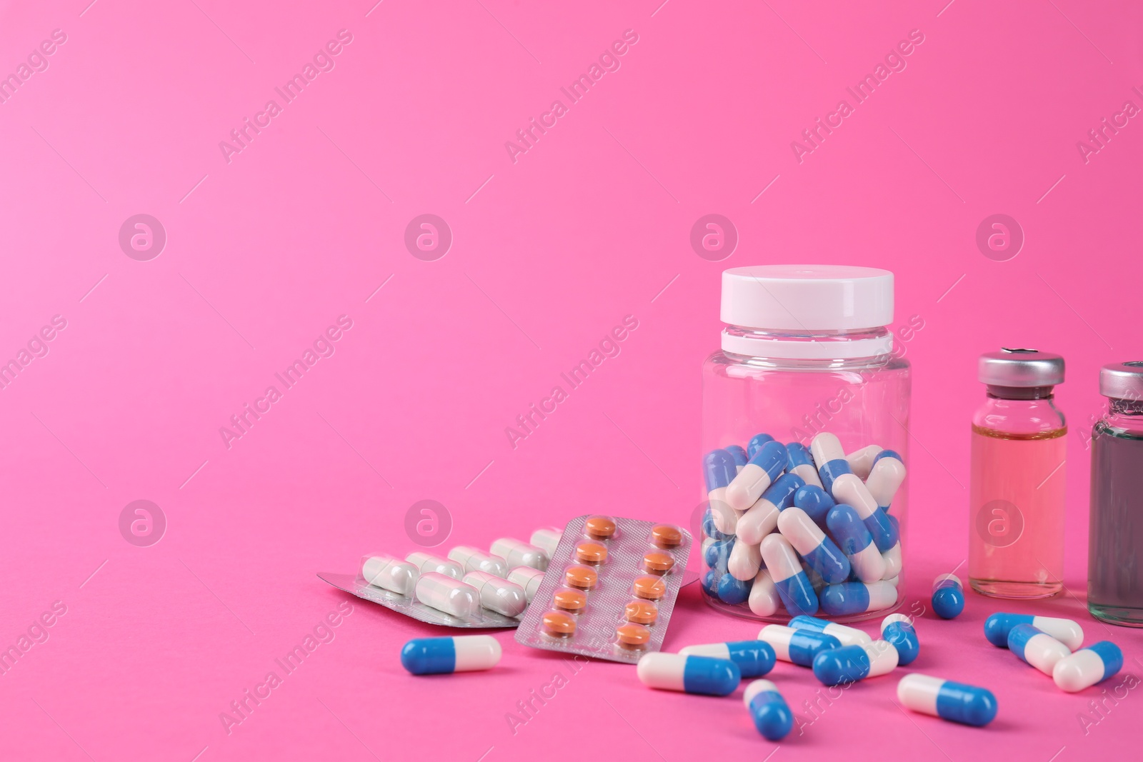 Photo of Pharmacist. Many different pills and vials with medication on pink background