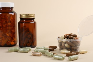 Pharmacist. Many different pills in plastic container and bottles on beige background