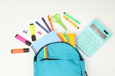 Backpack and different school supplies on white wooden background, flat lay