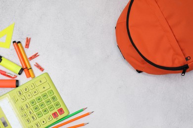 Photo of Flat lay composition with backpack and different school stationery on light grey table, space for text