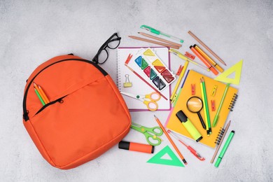 Photo of Flat lay composition with backpack and different school stationery on light grey table