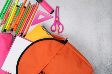 Photo of Flat lay composition with backpack and different school stationery on light grey table, space for text