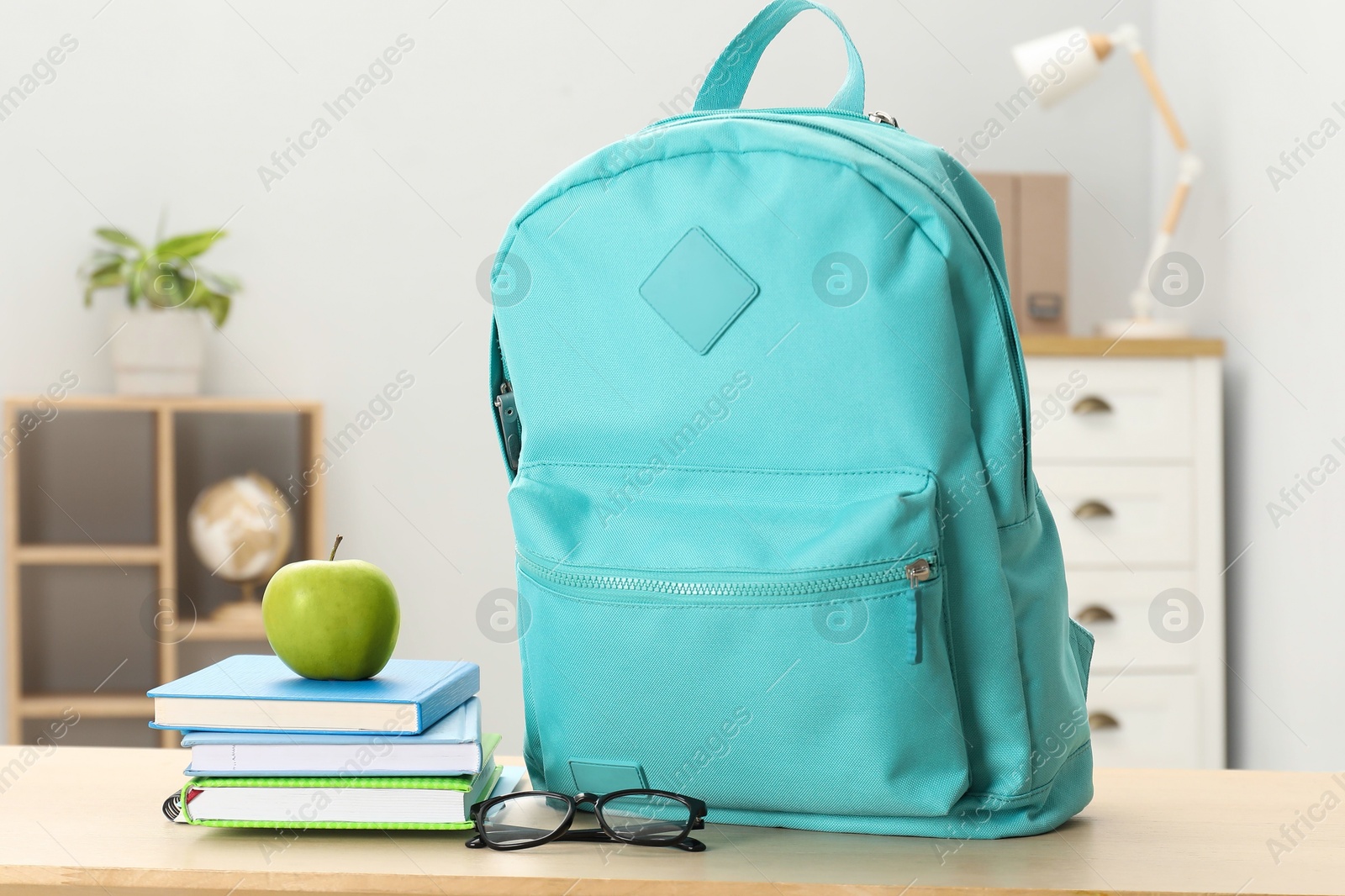 Photo of Backpack and different school stationery on wooden table indoors