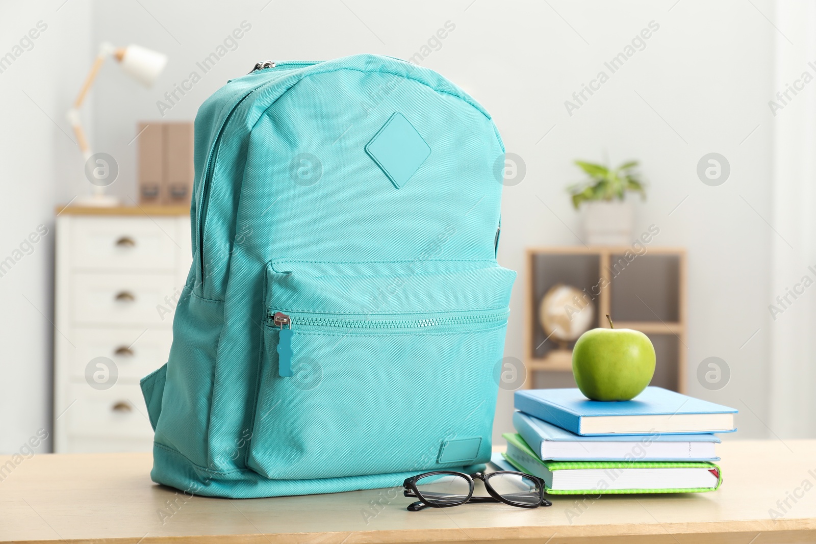 Photo of Backpack and different school stationery on wooden table indoors