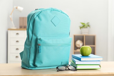 Photo of Backpack and different school stationery on wooden table indoors