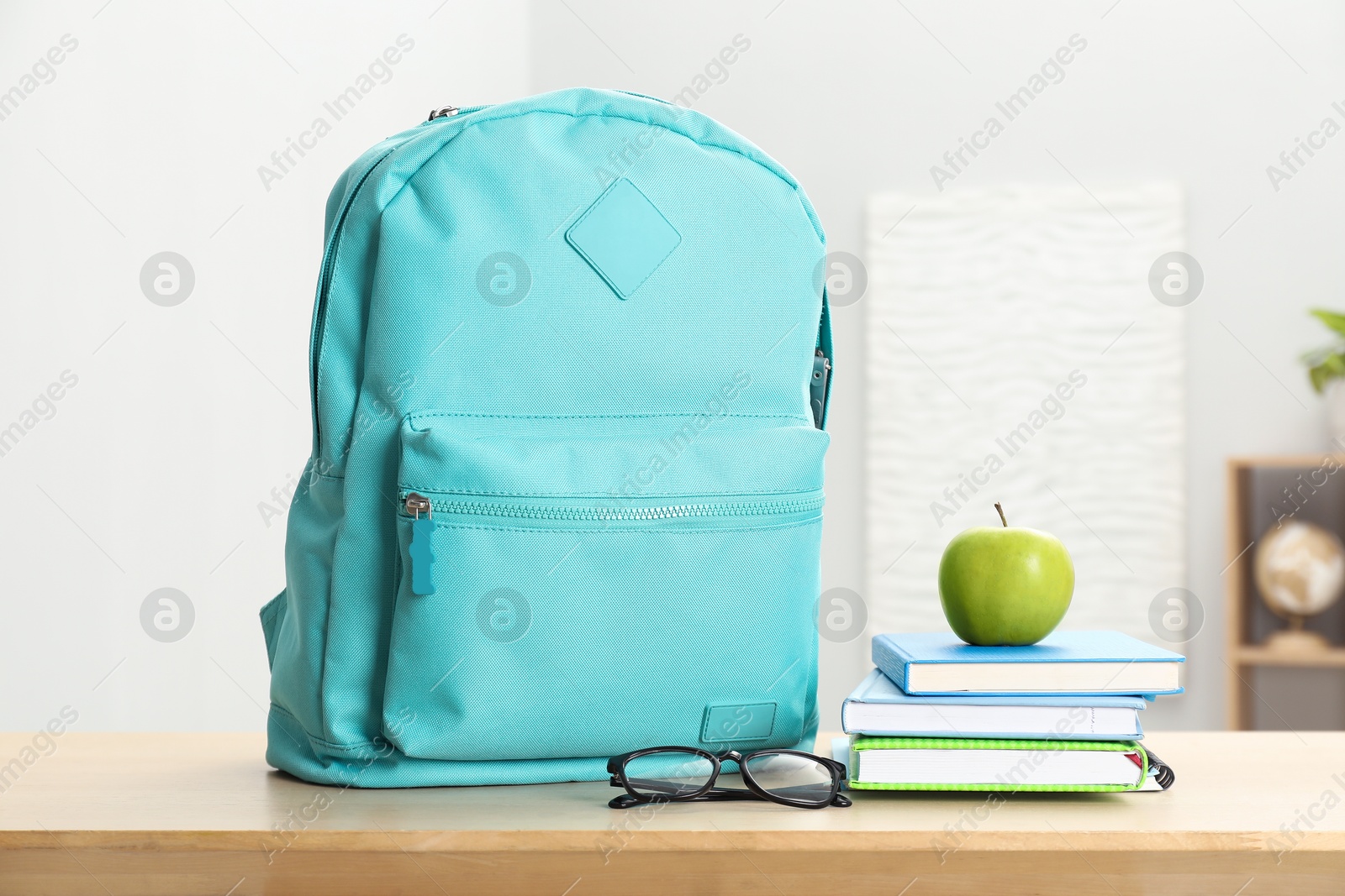 Photo of Backpack and different school stationery on wooden table indoors