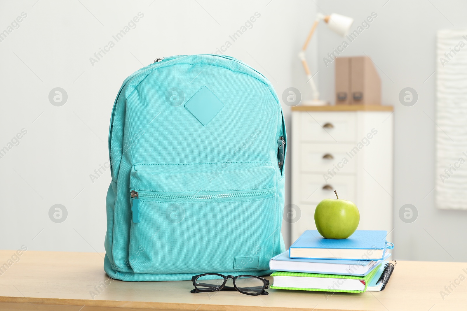 Photo of Backpack and different school stationery on wooden table indoors