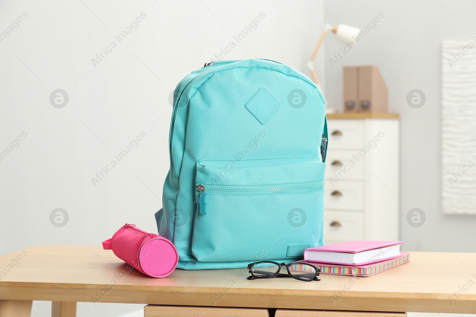 Photo of Backpack and different school stationery on wooden table indoors