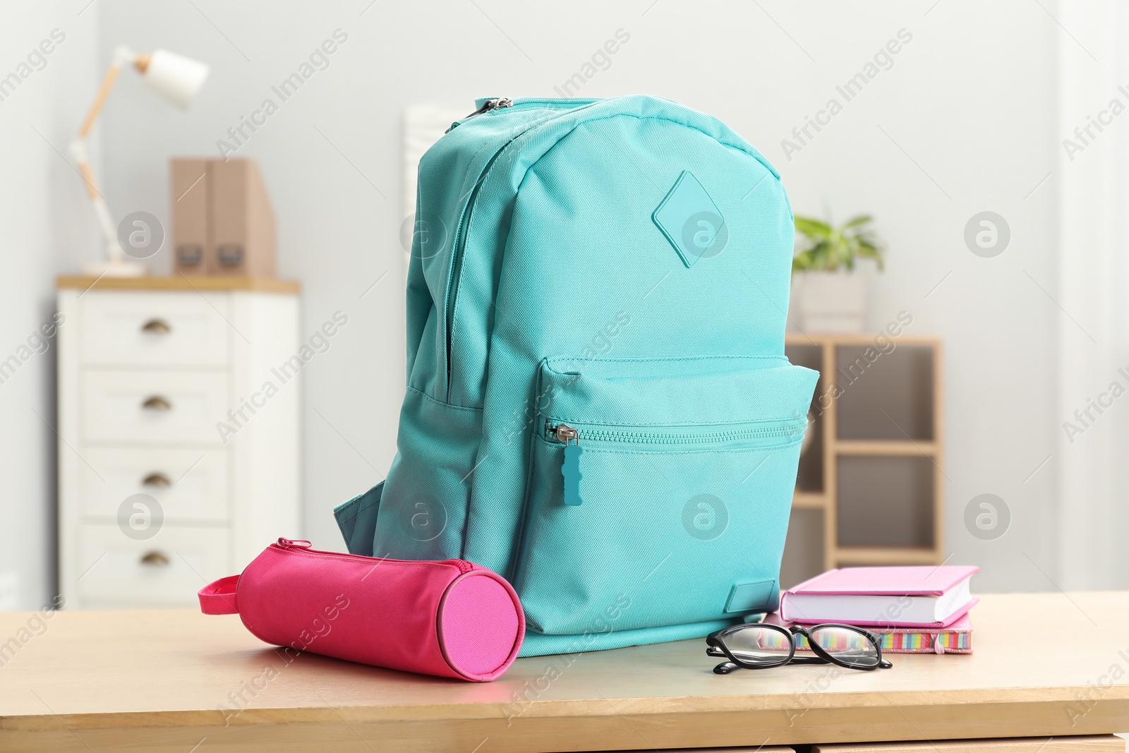 Photo of Backpack and different school stationery on wooden table indoors