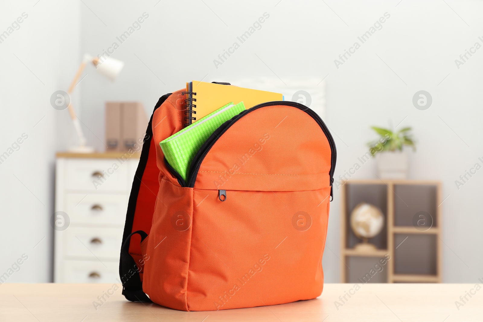 Photo of Backpack and different school stationery on wooden table indoors