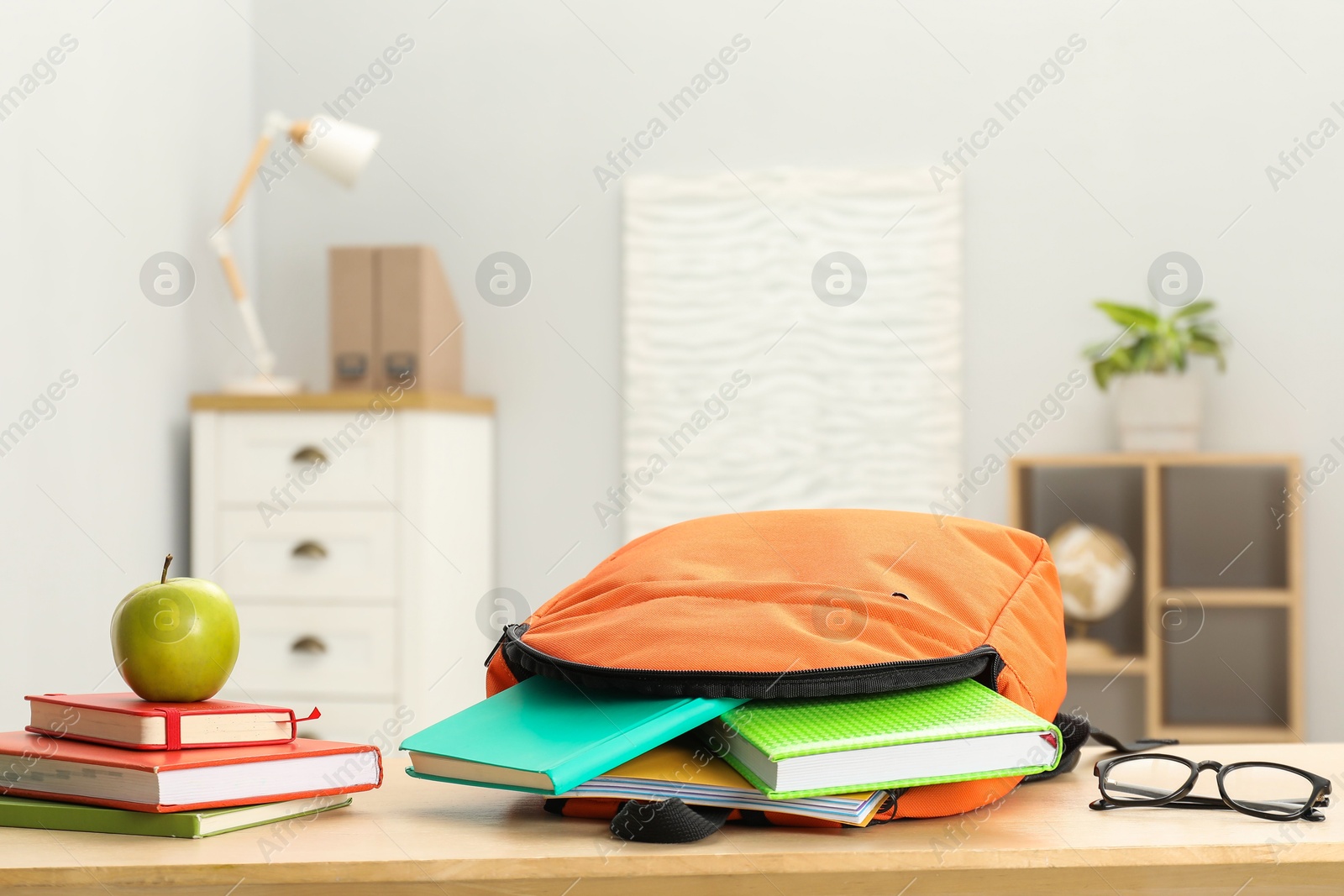 Photo of Backpack and different school stationery on wooden table indoors