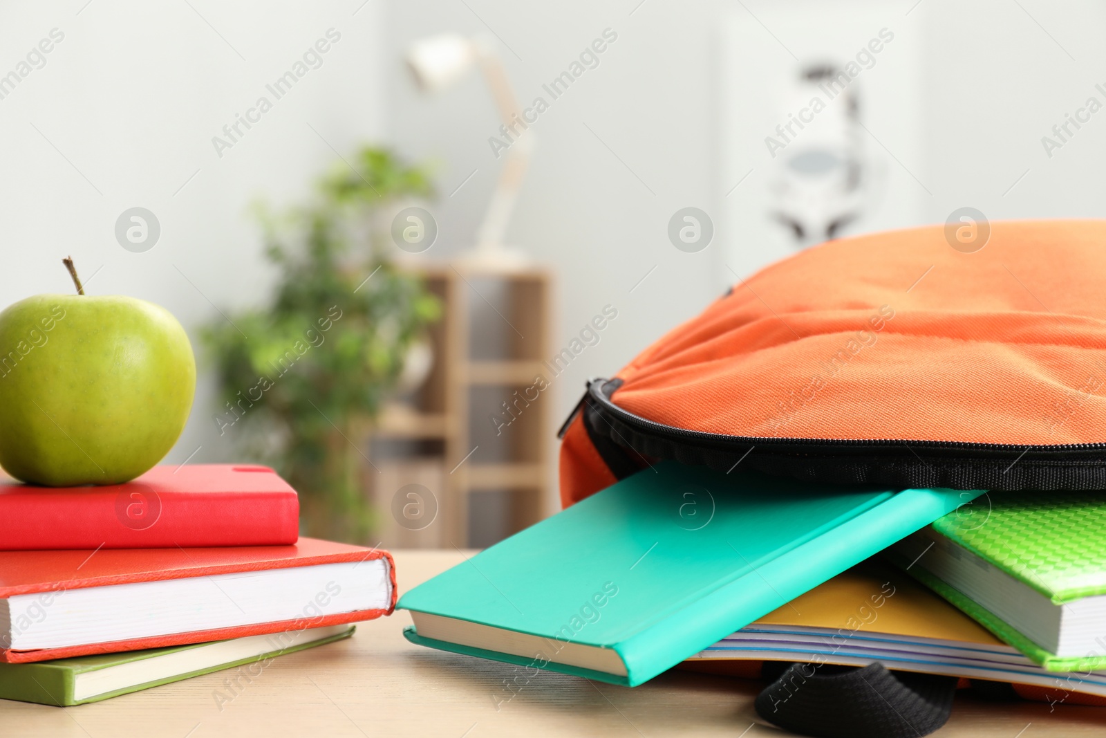 Photo of Backpack and different school stationery on wooden table indoors, closeup