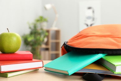 Photo of Backpack and different school stationery on wooden table indoors, closeup