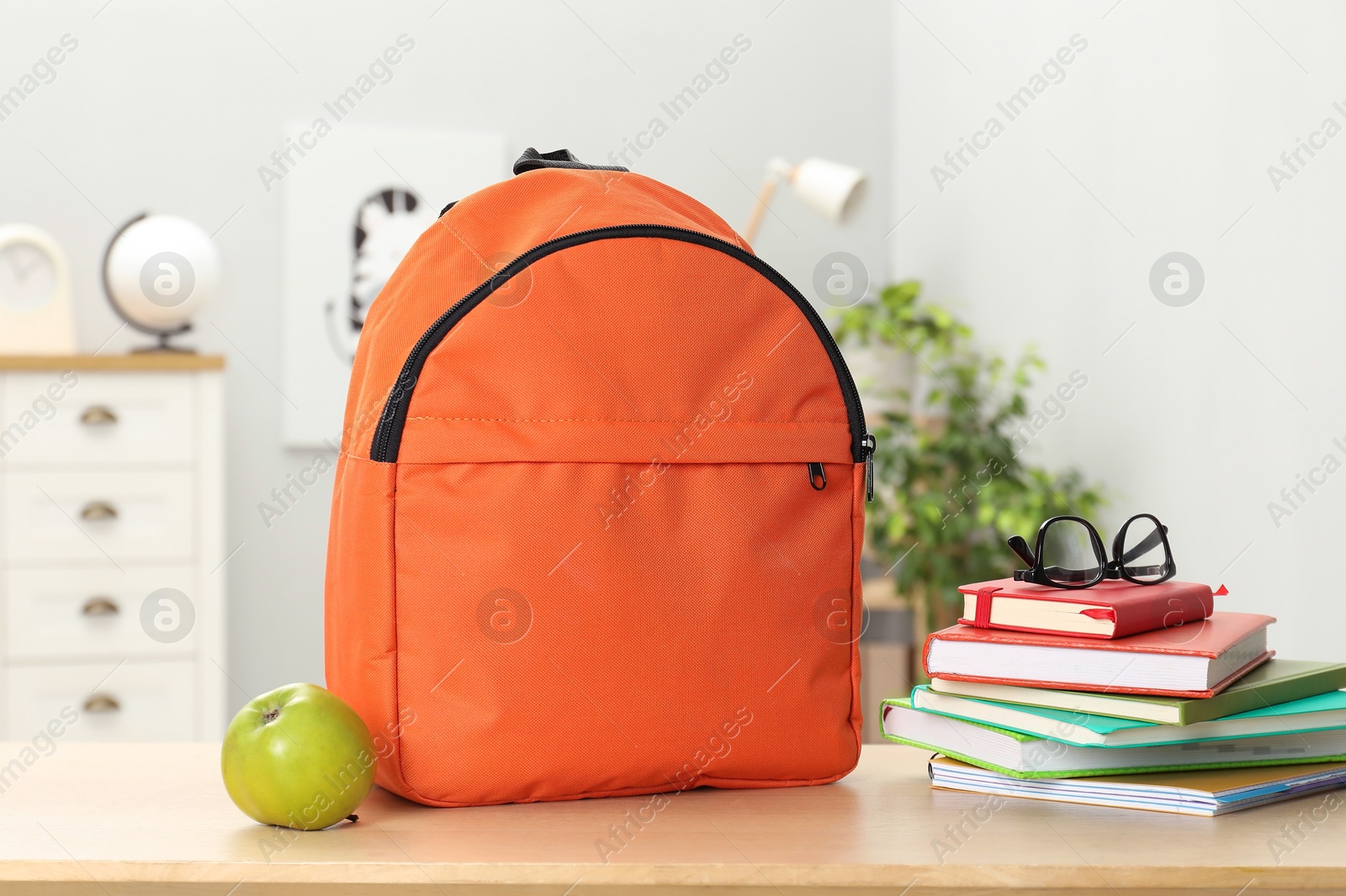 Photo of Backpack and different school stationery on wooden table indoors