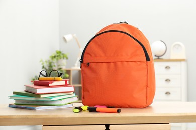 Photo of Backpack and different school stationery on wooden table indoors