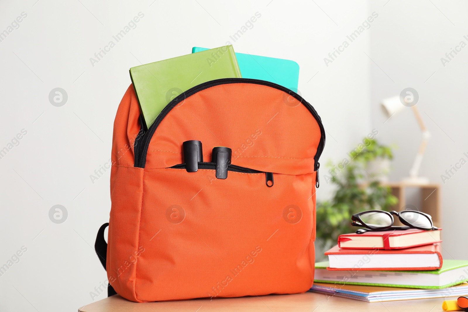 Photo of Backpack and different school stationery on wooden table indoors