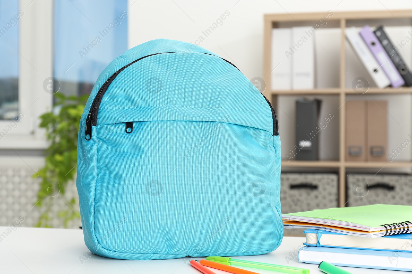 Photo of Backpack and different school stationery on white table indoors