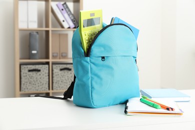 Photo of Backpack and different school stationery on white table indoors