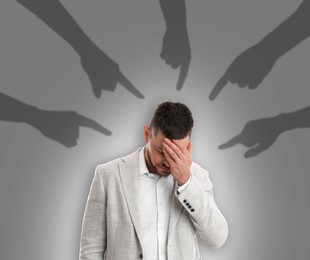 Silhouettes of people's hands pointing at upset man on grey background. Failure at work, responsibility, social pressure