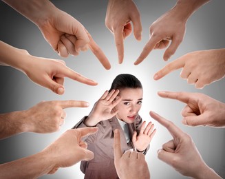 People pointing at scared woman on grey background. Social pressure, failure at work, responsibility