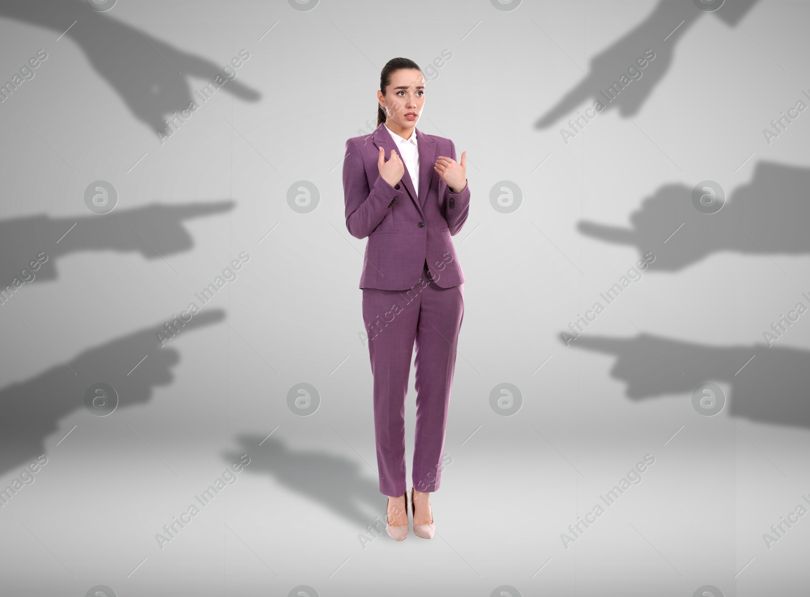 Image of Silhouettes of people's hands pointing at confused woman on grey background. Social pressure, failure at work, responsibility