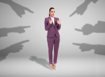 Silhouettes of people's hands pointing at confused woman on grey background. Social pressure, failure at work, responsibility