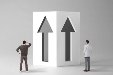 Image of Small men standing in front of huge arrows on grey background. Concept of career growth