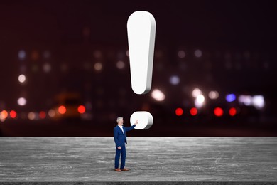 Image of Small businessman touching huge exclamation mark against blurred night cityscape. Concepts of achievement, startup, targeting