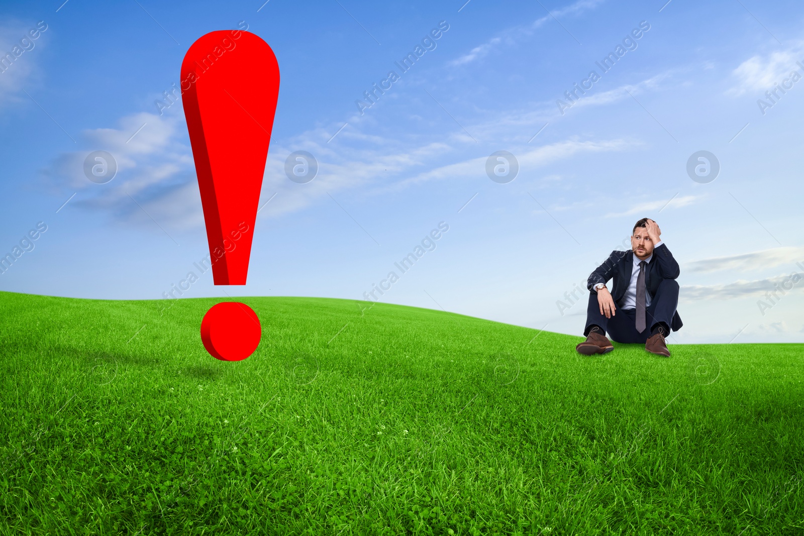 Image of Worried small businessman looking at huge red exclamation mark on green meadow. Concepts of workload, problem