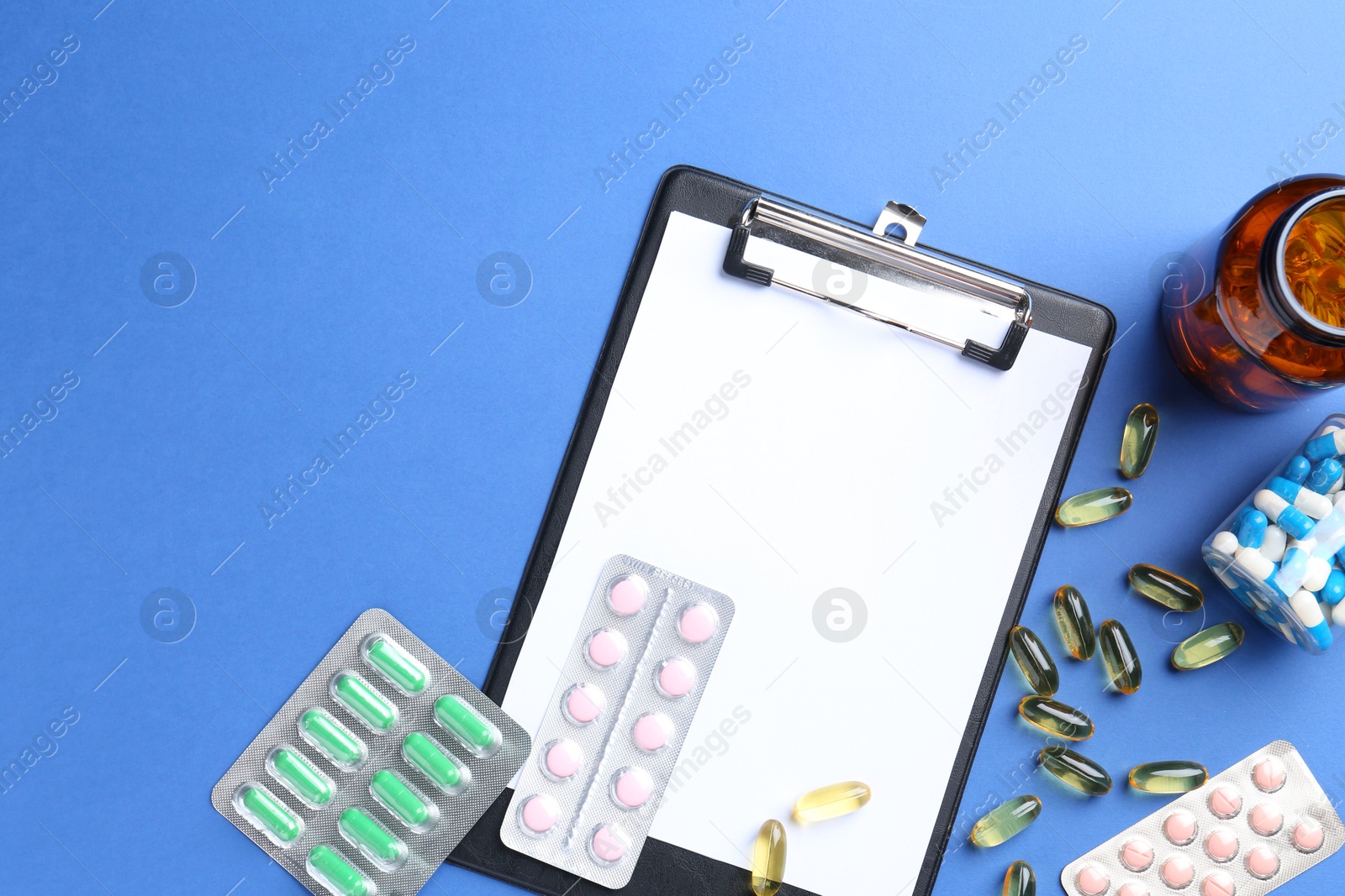 Photo of Pharmacist concept. Flat lay composition with clipboard and pills on blue background, space for text