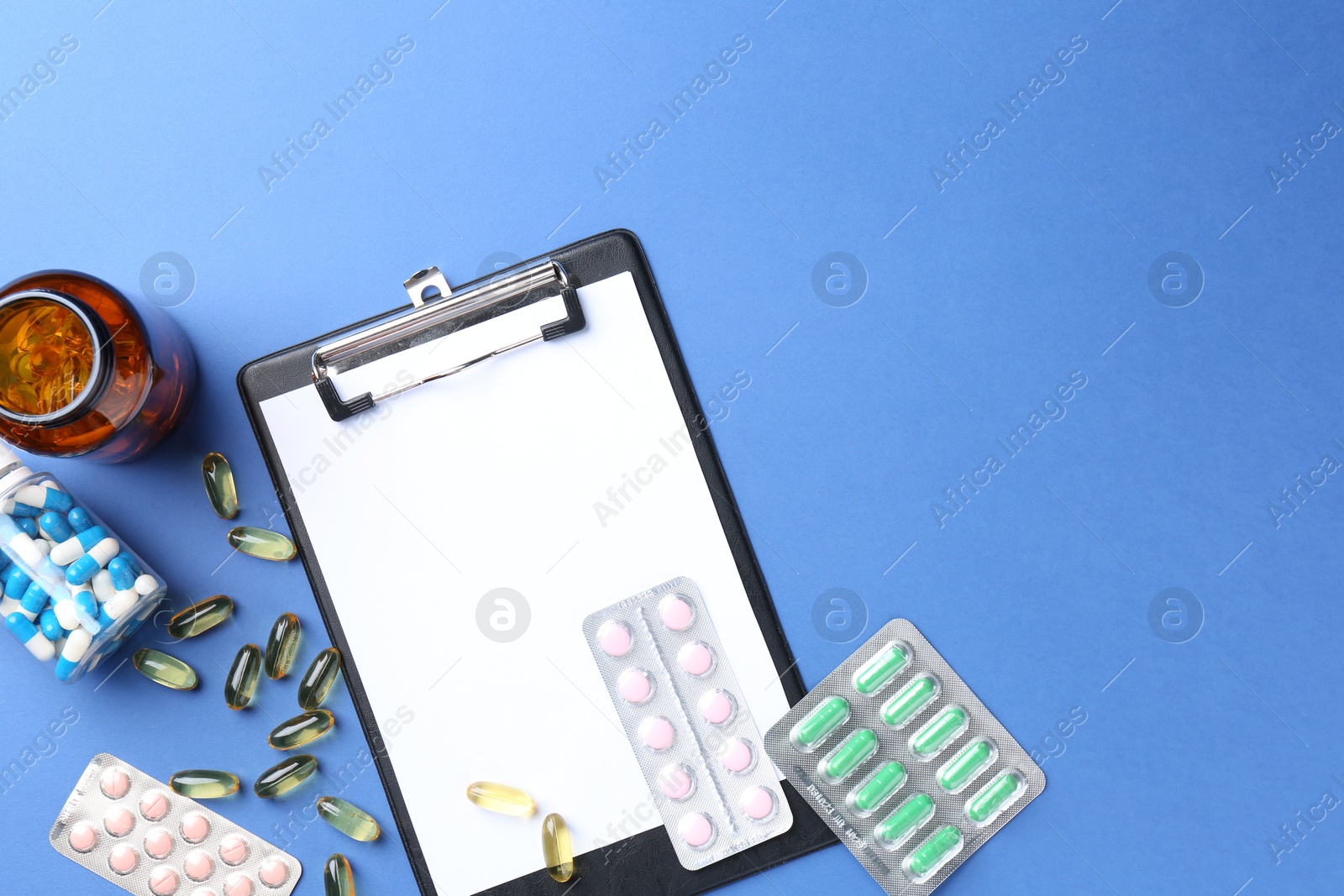 Photo of Pharmacist concept. Flat lay composition with clipboard and pills on blue background, space for text