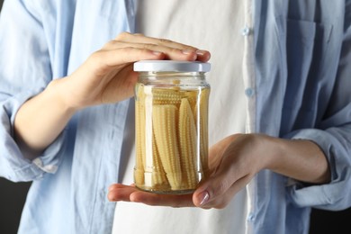 Photo of Woman with jar of tasty pickled yellow baby corns, closeup