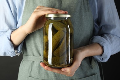 Photo of Woman with jar of tasty pickled cucumbers on gray background, closeup