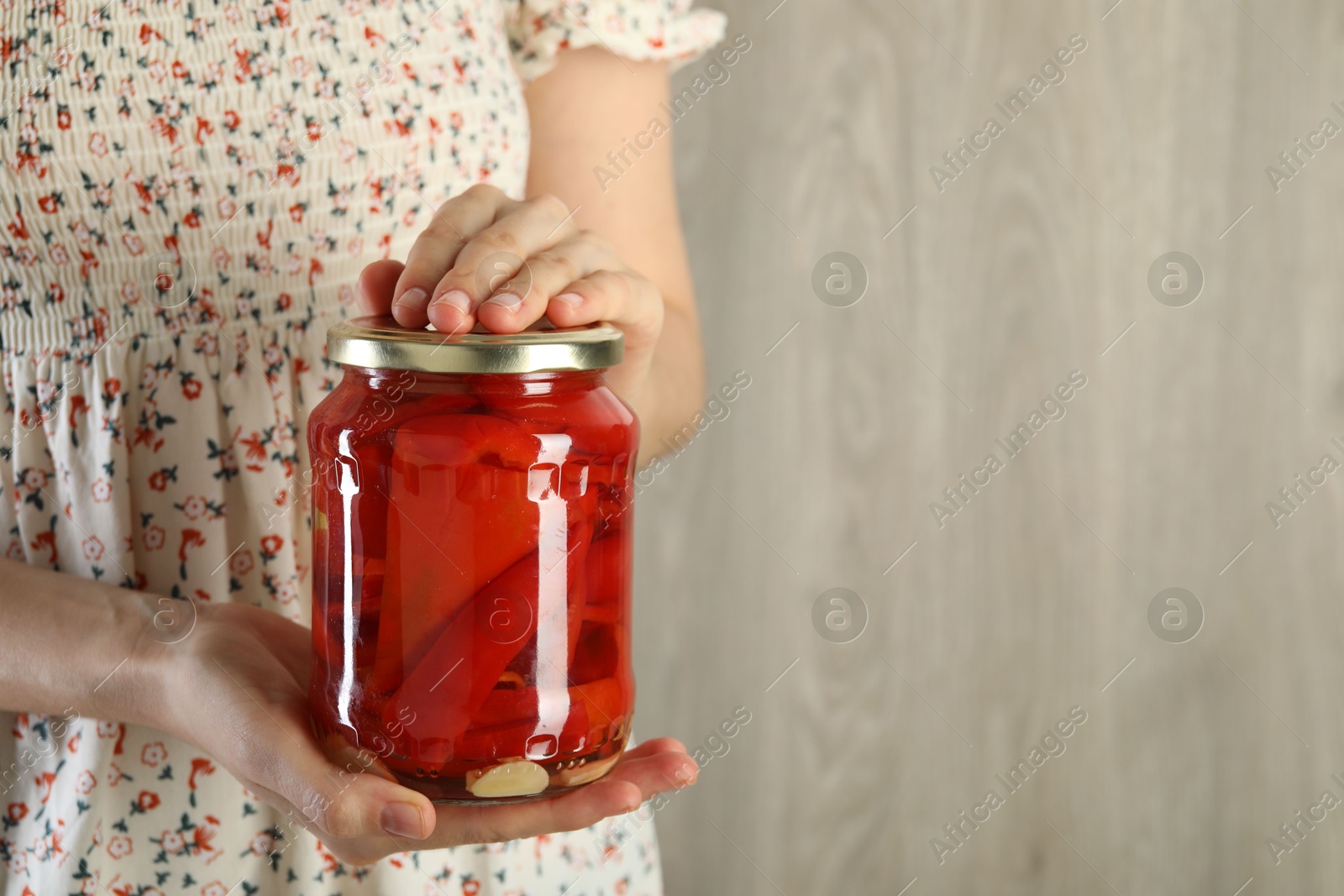 Photo of Woman with jar of tasty pickled peppers indoors, closeup. Space for text