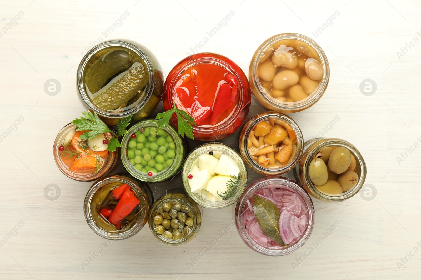 Photo of Different pickled products in jars on light wooden table, top view