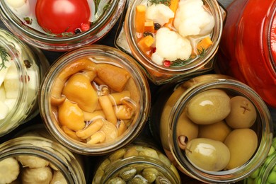 Different pickled products in jars on table, top view