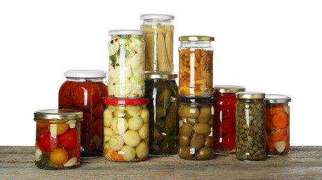 Photo of Different pickled products in jars on wooden table against white background