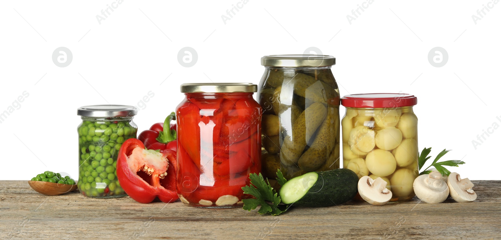 Photo of Different pickled products in jars and fresh ingredients on wooden table against white background