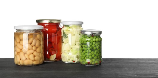 Photo of Different pickled products in jars on dark wooden table against white background. Space for text