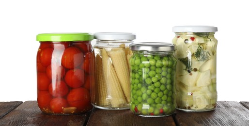 Photo of Different pickled products in jars on wooden table against white background