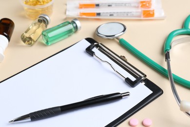 Pharmacist concept. Clipboard, stethoscope, vials and pills on beige background, closeup