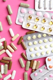 Pharmacist concept. Flat lay composition with many different pills on pink background