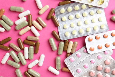 Pharmacist concept. Flat lay composition with many different pills on pink background