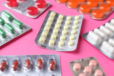 Pharmacist concept. Many different pills on pink background, closeup