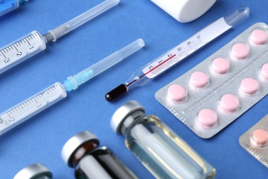 Pharmacist concept. Vials, syringes and pills on blue background, closeup