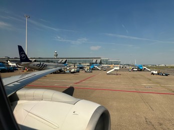 Photo of Haarlemmermeer, Netherlands - July 30, 2024: Modern airplanes in Amsterdam Airport Schiphol, view through plane window