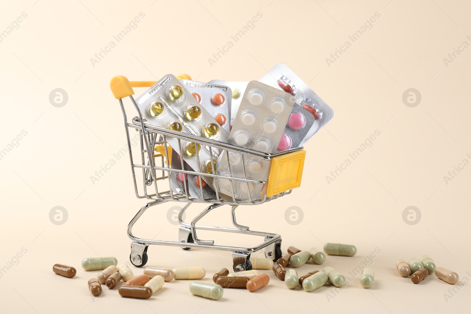 Photo of Pharmacist. Many different pills in small shopping cart on beige background