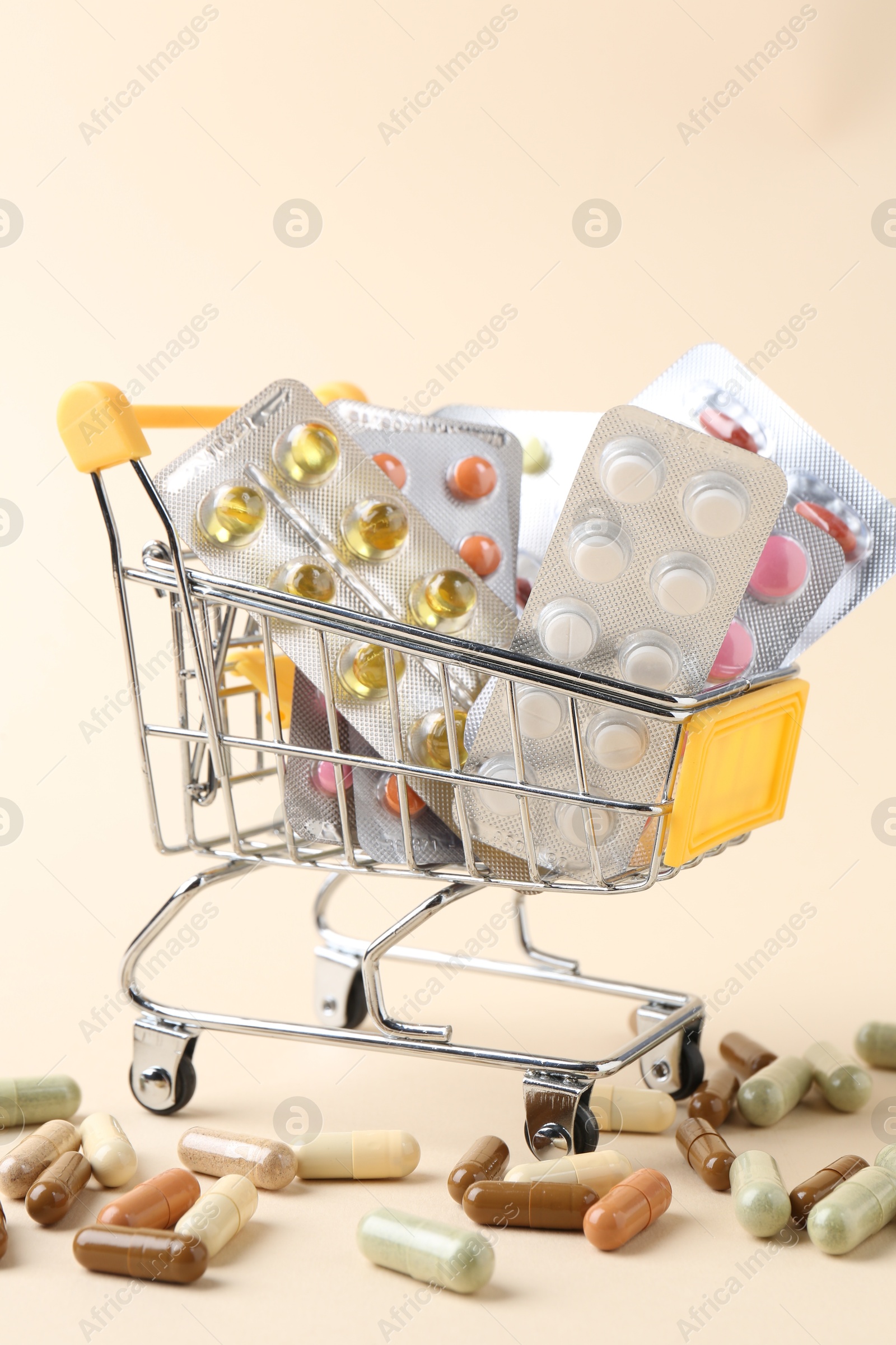 Photo of Pharmacist. Many different pills in small shopping cart on beige background